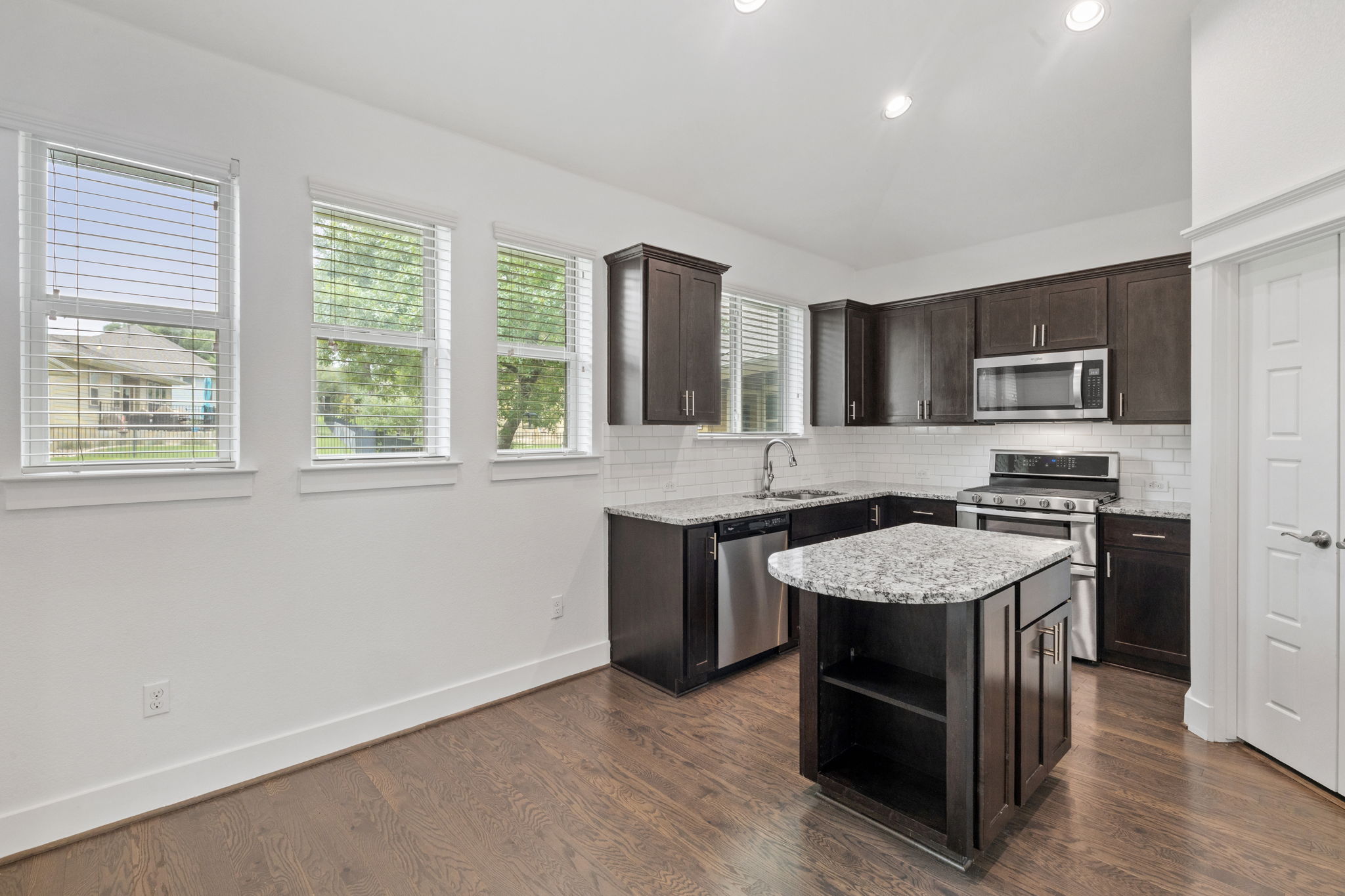 1765 Rowdy Loop, Unit 47 Leander, TX 78641 - Photo 17 of 39 Modern kitchen featuring dark wood cabinetry, stainless steel appliances, granite countertops, and a white subway tile backsplash