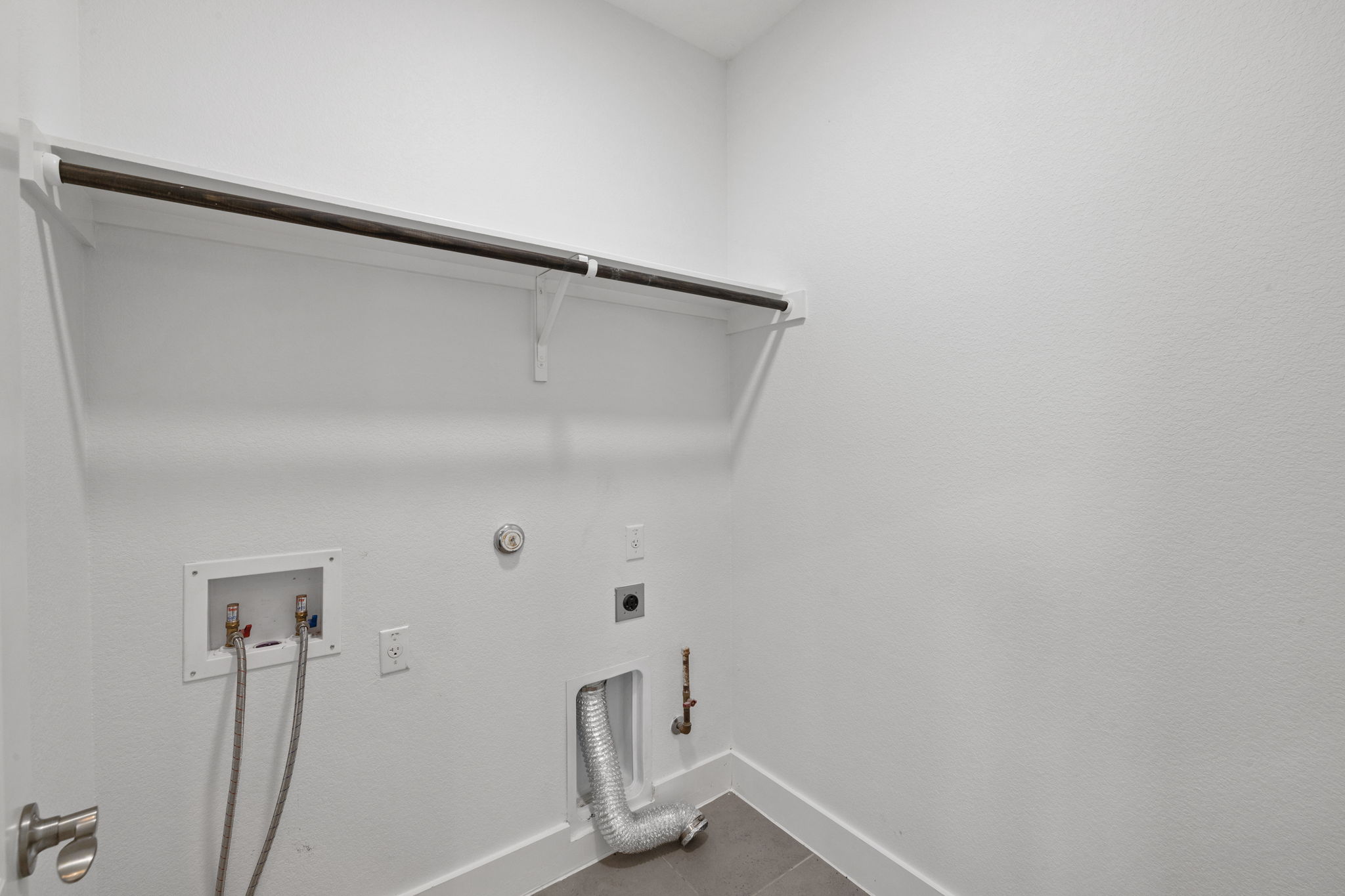 1765 Rowdy Loop, Unit 47 Leander, TX 78641 - Photo 19 of 39 Dedicated utility space featuring a built-in hanging rod, wall-mounted shelving support, and contemporary tile flooring