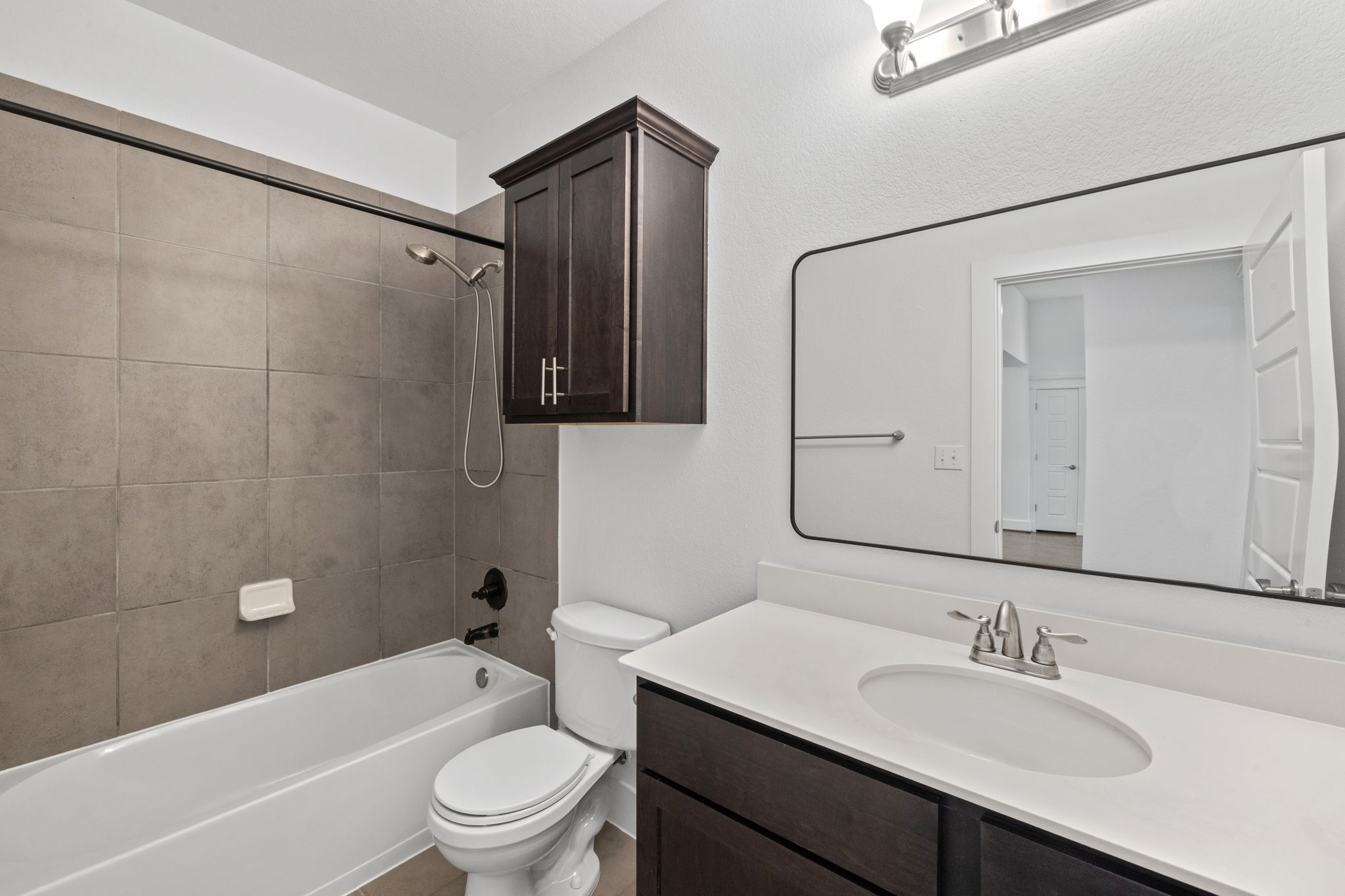 1765 Rowdy Loop, Unit 47 Leander, TX 78641 - Photo 24 of 39 Bathroom featuring a white tub, shower with large format gray wall tile, and a dark wood-finish vanity with a white countertop