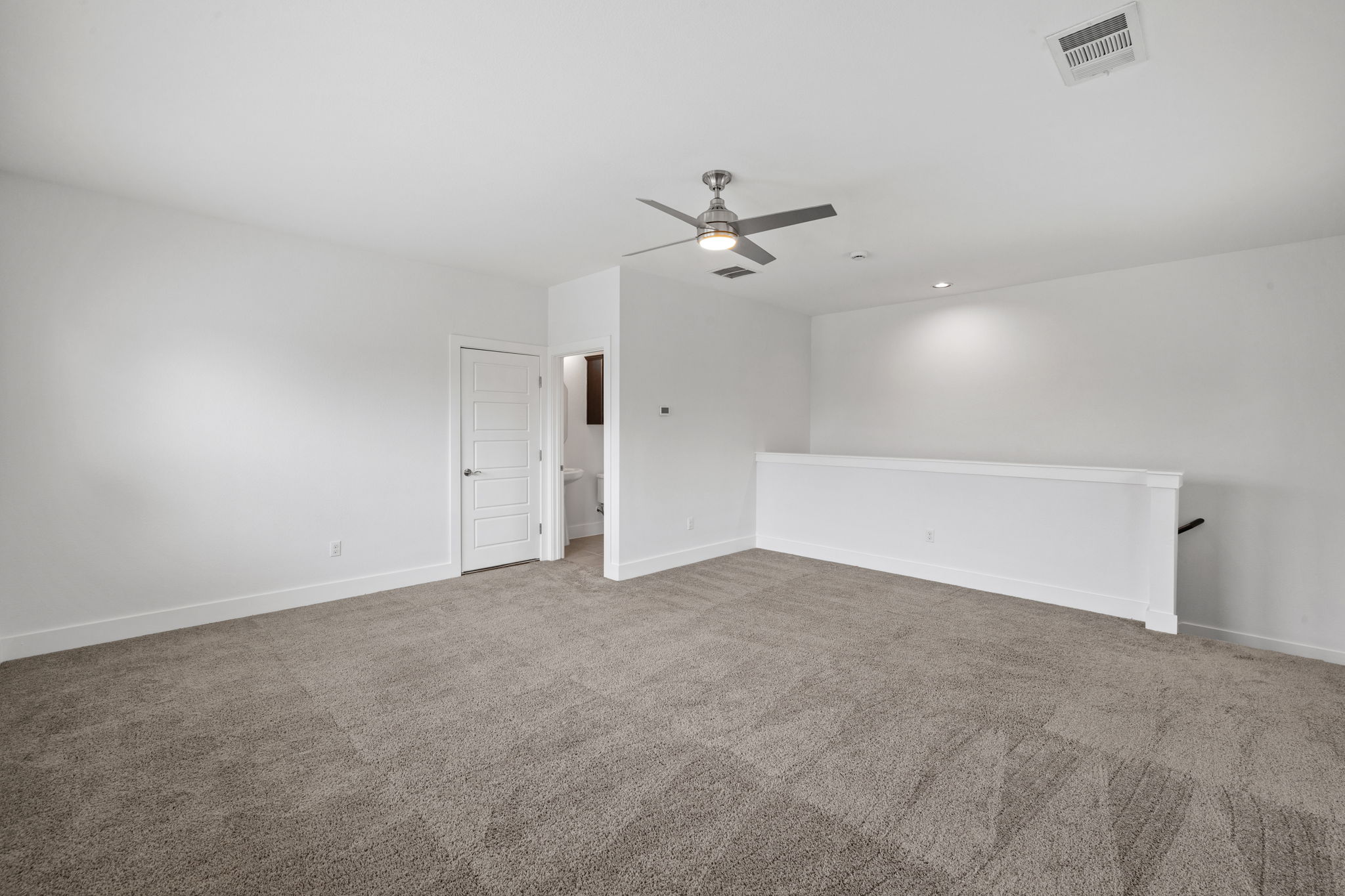 1765 Rowdy Loop, Unit 47 Leander, TX 78641 - Photo 35 of 39 Spacious loft area featuring neutral-toned carpeting, a modern ceiling fan with lighting, recessed ceiling lights, a solid white banister, and a paneled interior door