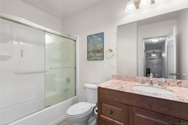 a bathroom with a granite countertop toilet a sink and a mirror