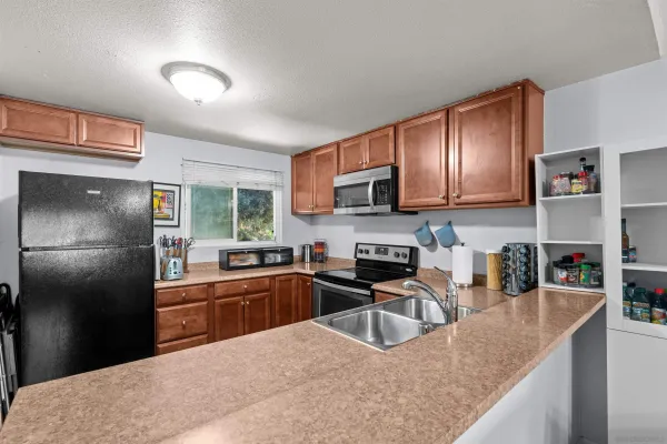 a kitchen with granite countertop a sink a stove and refrigerator