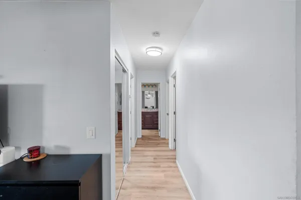 a view of a hallway with wooden floor and a bathroom