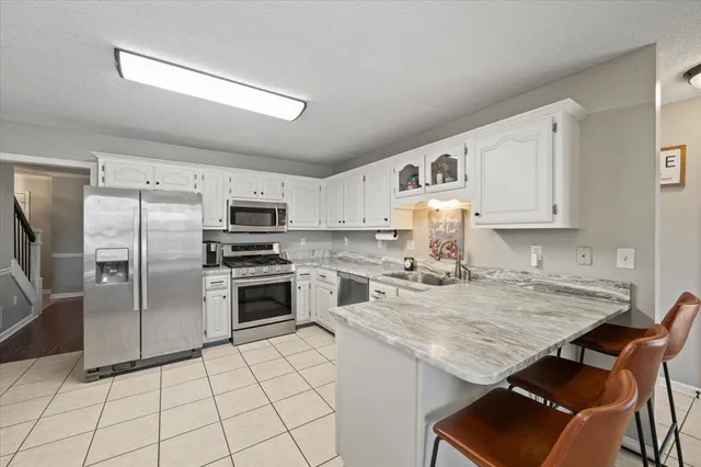 a kitchen with granite countertop a stove a sink dishwasher a refrigerator and cabinets with wooden floor