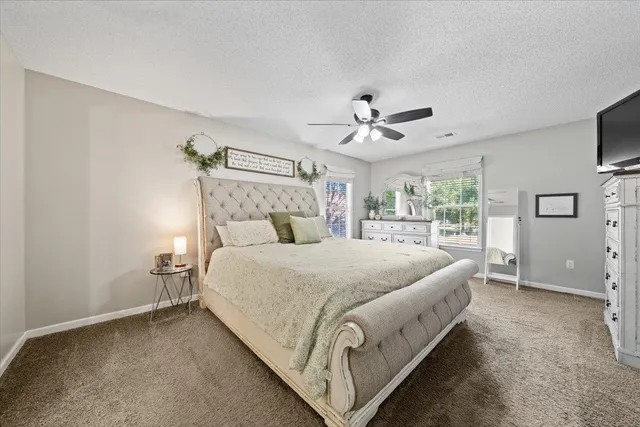 a spacious bedroom with a bed a window and a flat screen tv