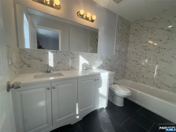 a bathroom with a granite countertop sink a toilet and a mirror