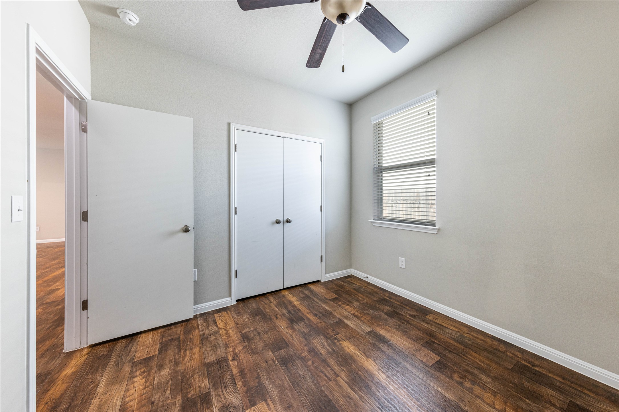 368 Wapiti Road Buda, TX 78610 - Photo 11 of 20 Room featuring wood-finish flooring, light gray walls, a window with horizontal blinds, a ceiling fan, and a bi-fold closet