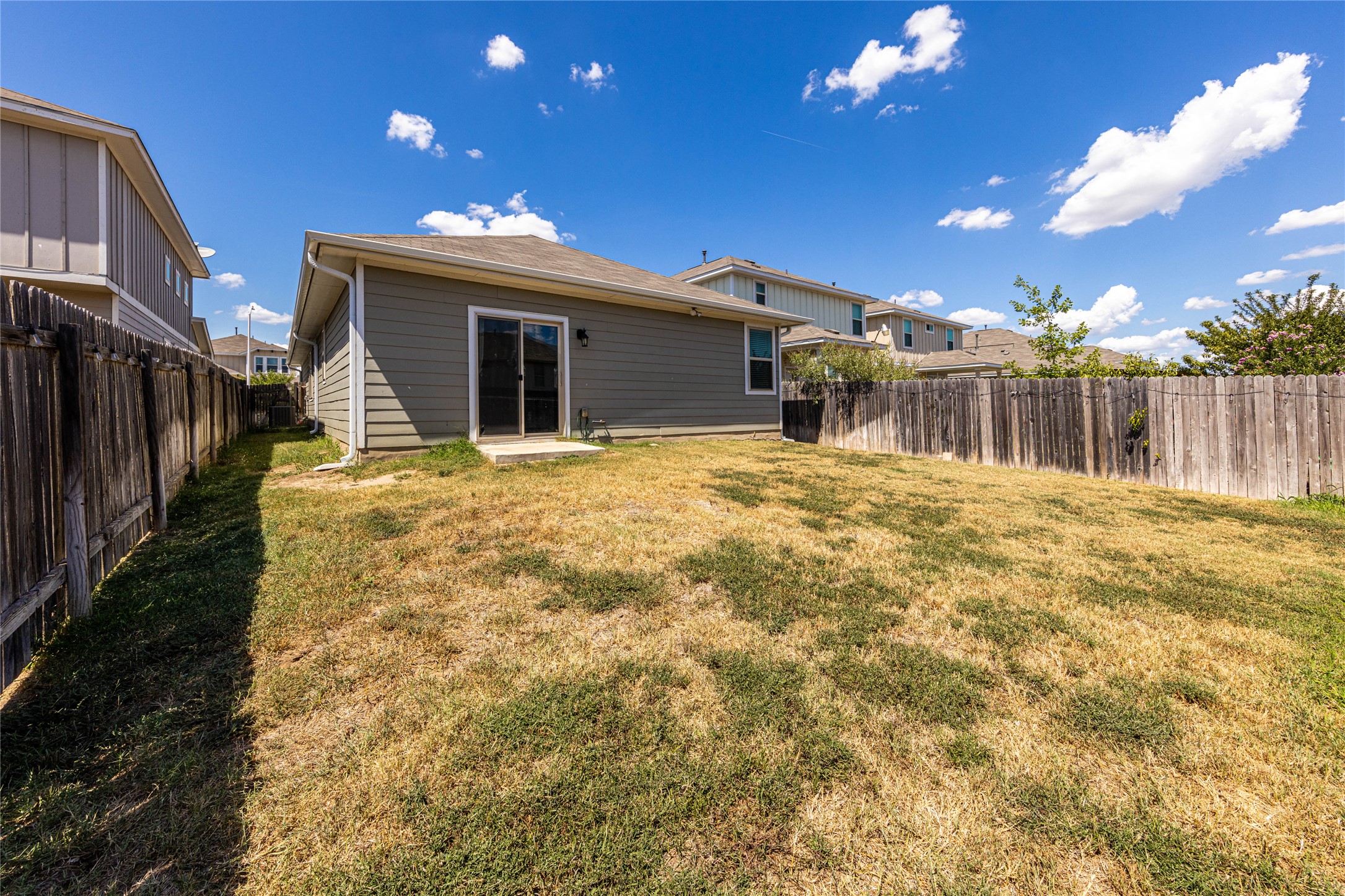 368 Wapiti Road Buda, TX 78610 - Photo 16 of 20 Expansive backyard featuring a privacy fence, concrete patio, and sliding glass door access to the interior