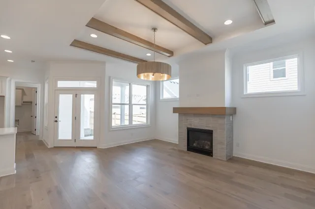an empty room with wooden floor fireplace and windows