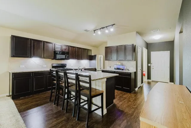 a kitchen with kitchen island granite countertop wooden floors and wooden cabinets