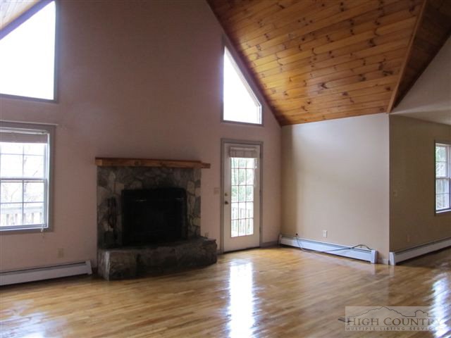 3192 Wildcat Road Deep Gap, NC 28618 - Photo 19 of 24 an empty room with wooden floor windows and fireplace
