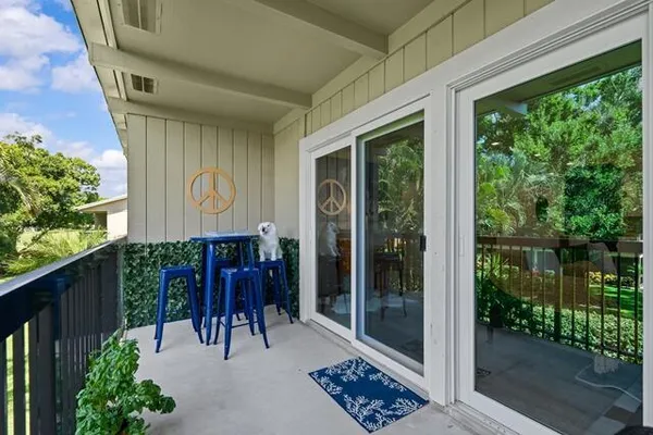 a view of a chairs and table in the balcony next to a yard