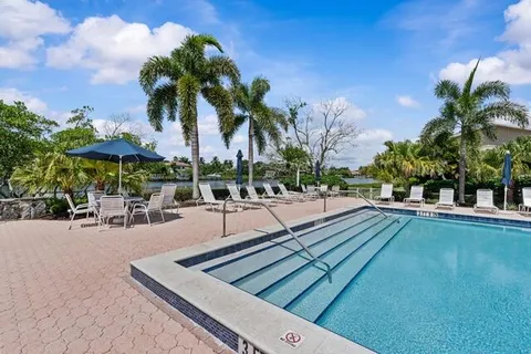 a view of swimming pool with outdoor seating and trees in the background