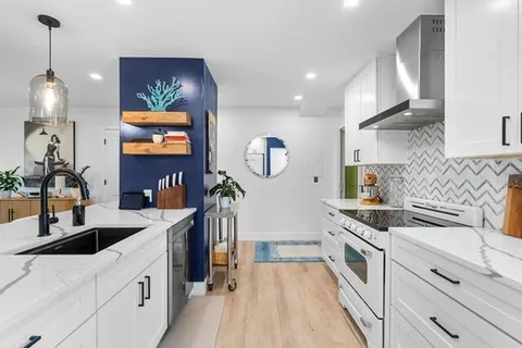 a kitchen that has a sink a stove and a wooden floor