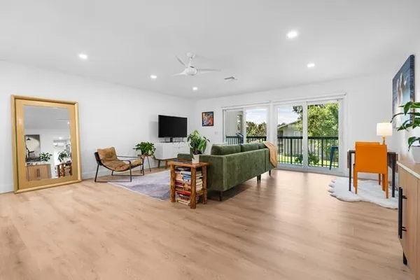 a living room with furniture a flat screen tv and a floor to ceiling window