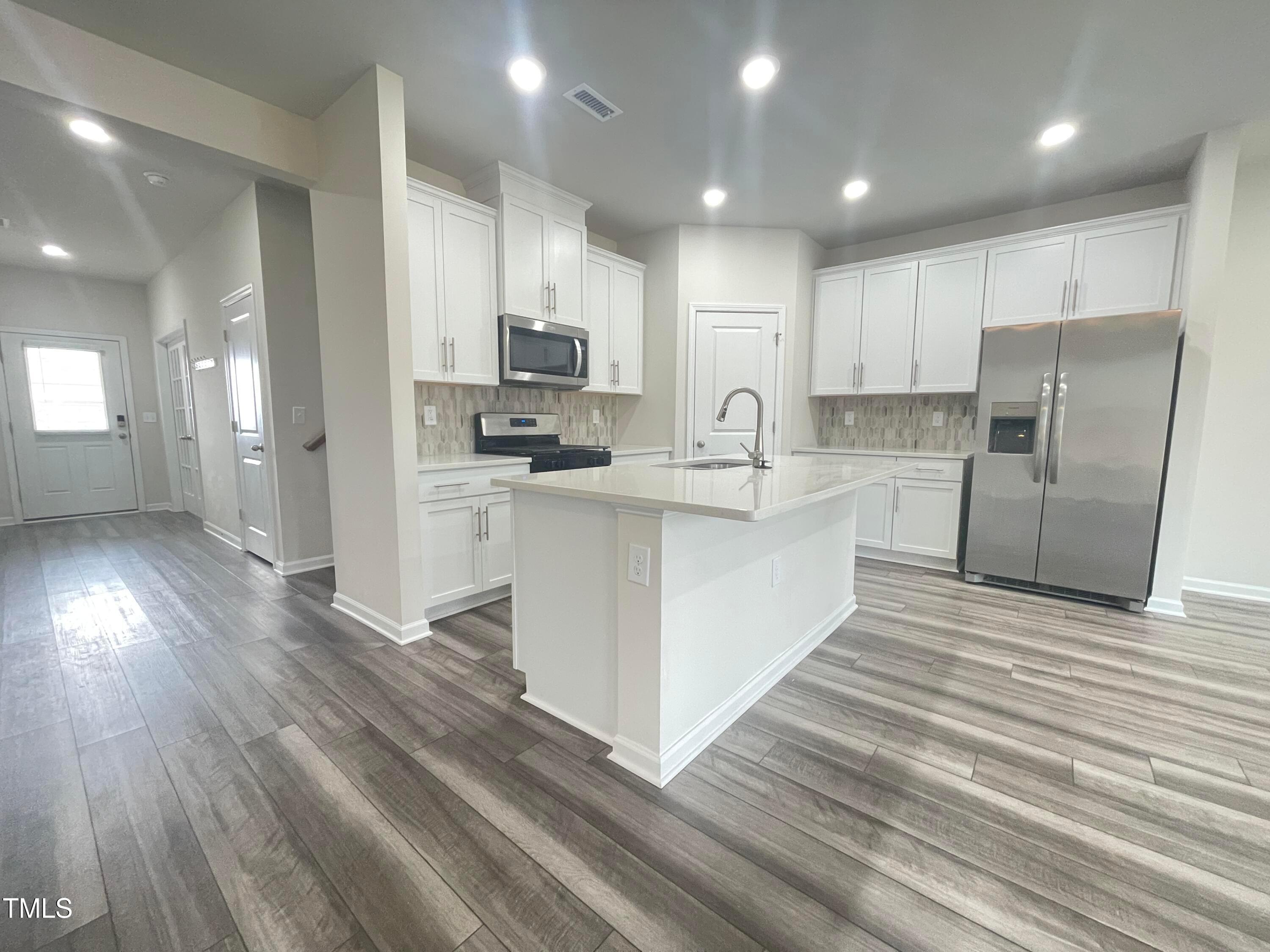 119 Red Valor Street Garner, NC 27529 - Photo 7 of 27 a large kitchen with stainless steel appliances lots of counter space and wooden floor