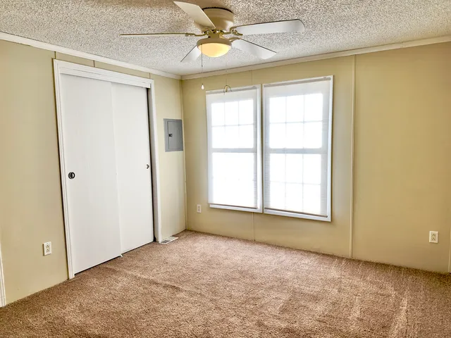 an empty room with windows and fan
