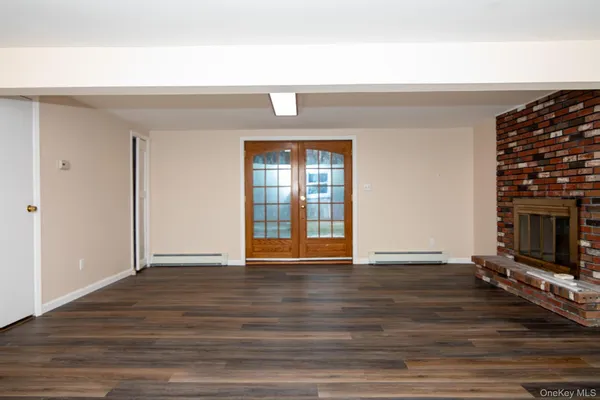 a view of an empty room with wooden floor and a fireplace