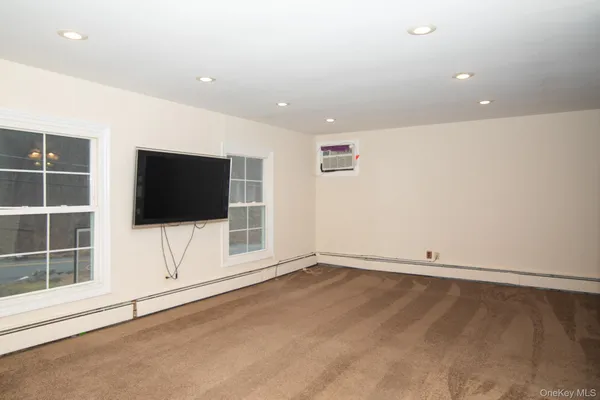a view of an empty room with a flat tv screen and a window