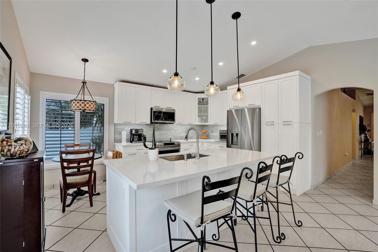 13621 Southwest 18th Street Miramar, FL 33027 - Photo 13 of 45 a kitchen view with stainless steel appliances kitchen island granite countertop a table chairs and a refrigerator
