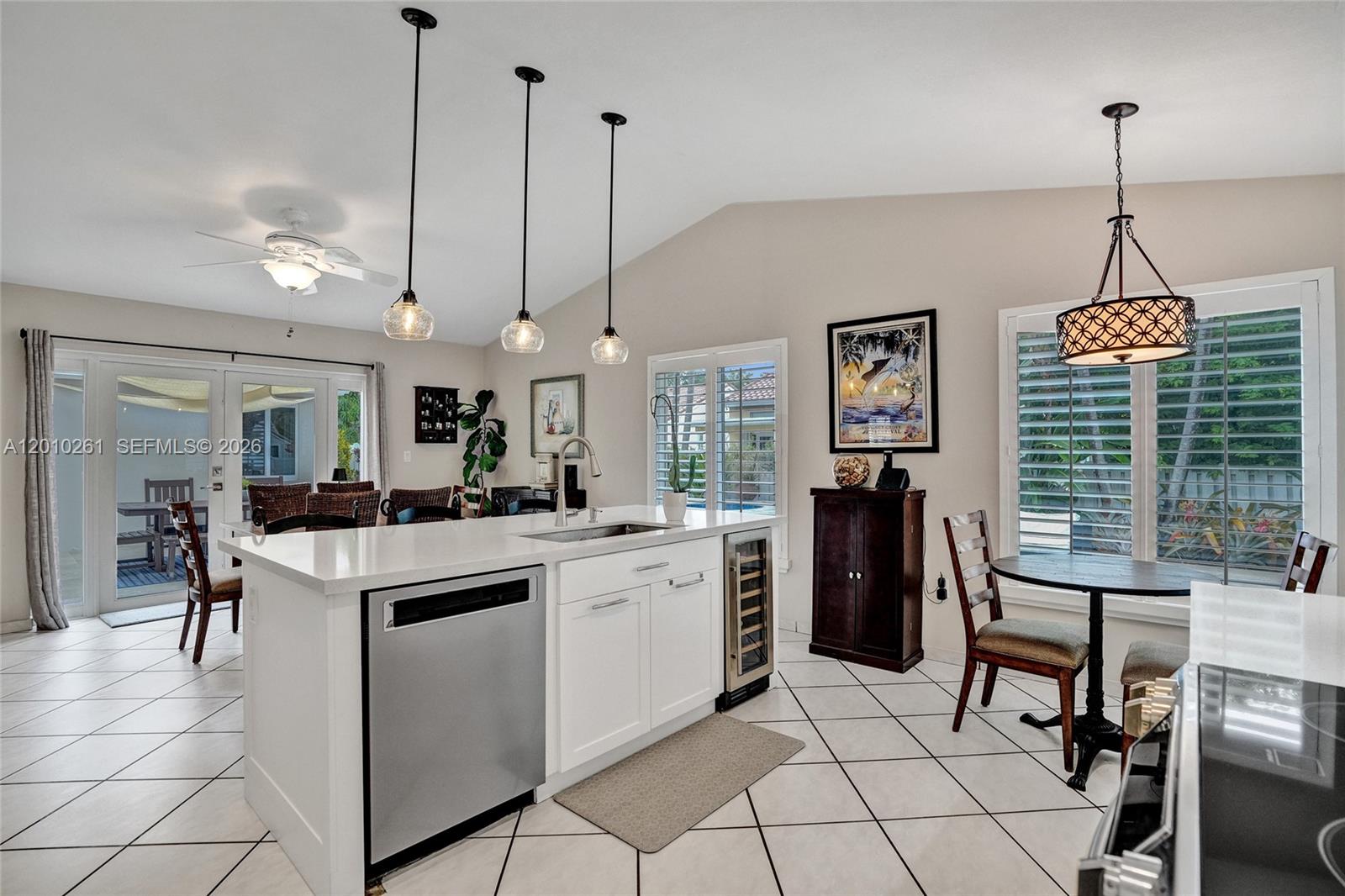 13621 Southwest 18th Street Miramar, FL 33027 - Photo 14 of 45 a kitchen with stainless steel appliances kitchen island granite countertop a stove a sink a dining table with chairs and white cabinets