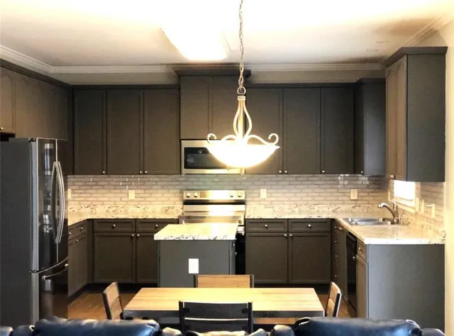 a kitchen with stainless steel appliances kitchen island granite countertop a refrigerator and a stove top oven