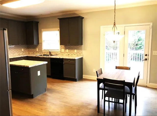 a kitchen with stainless steel appliances granite countertop a sink a stove a dining table and chairs