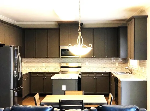 a kitchen with stainless steel appliances kitchen island granite countertop a refrigerator and a stove top oven