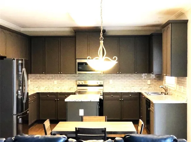 a kitchen with stainless steel appliances kitchen island granite countertop a refrigerator and a stove top oven