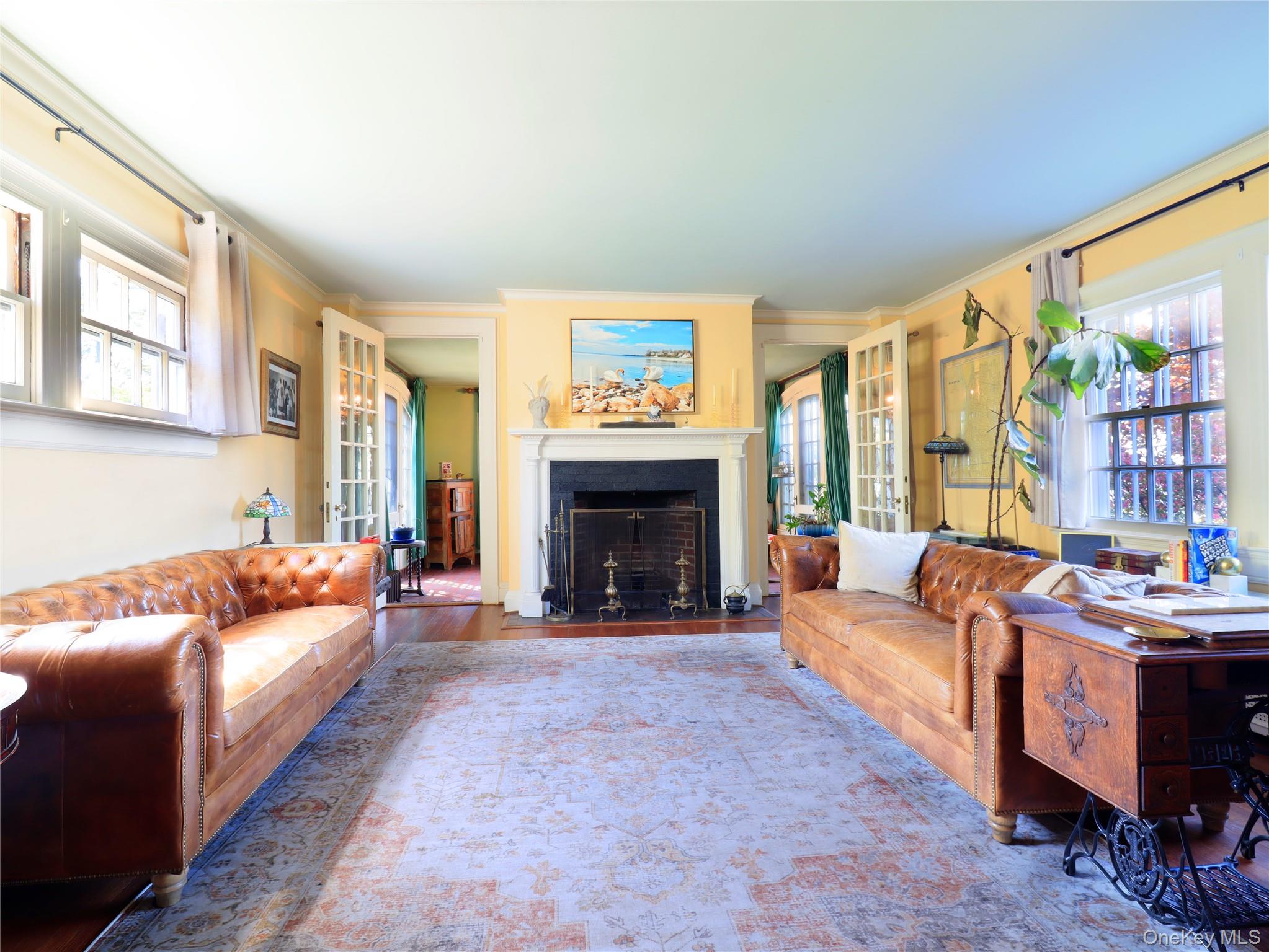 11-20 Shore Road Queens, NY 11363 - Photo 24 of 45 Spacious living area featuring a central fireplace with a classic mantel, hardwood flooring, multiple large windows, and French doors