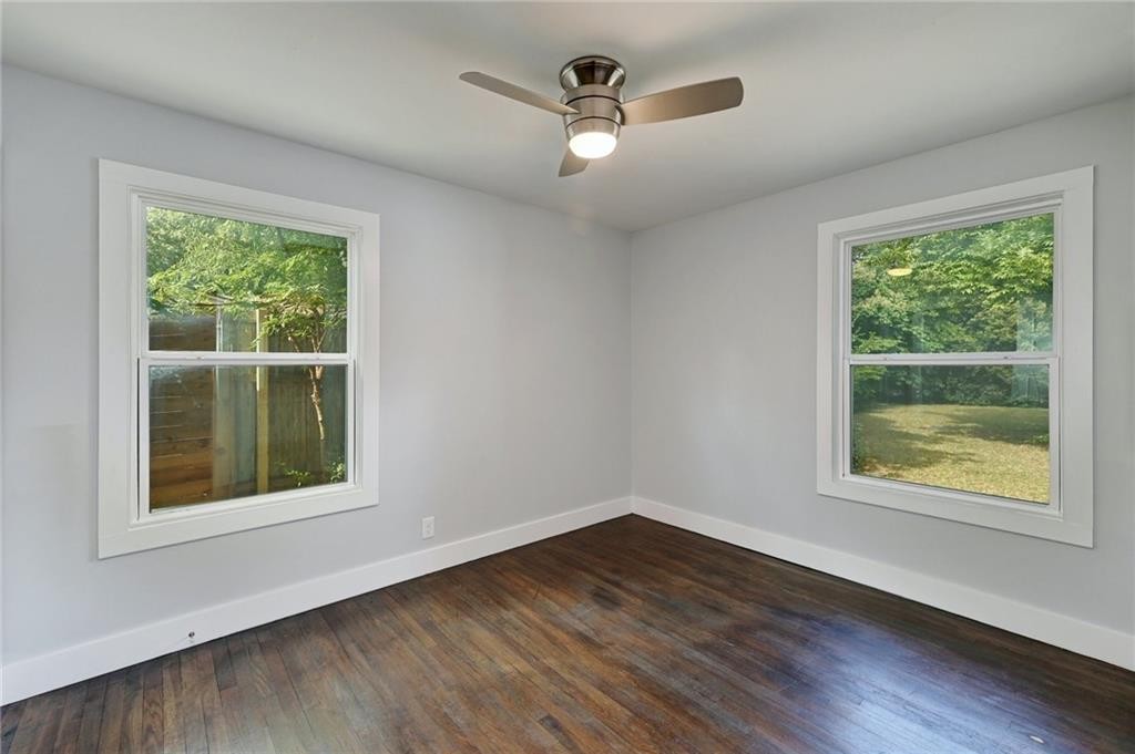 8318 Burrell Drive Austin, TX 78757 - Photo 12 of 27 Unfurnished room with healthy amount of natural light, dark wood-style floors, and ceiling fan