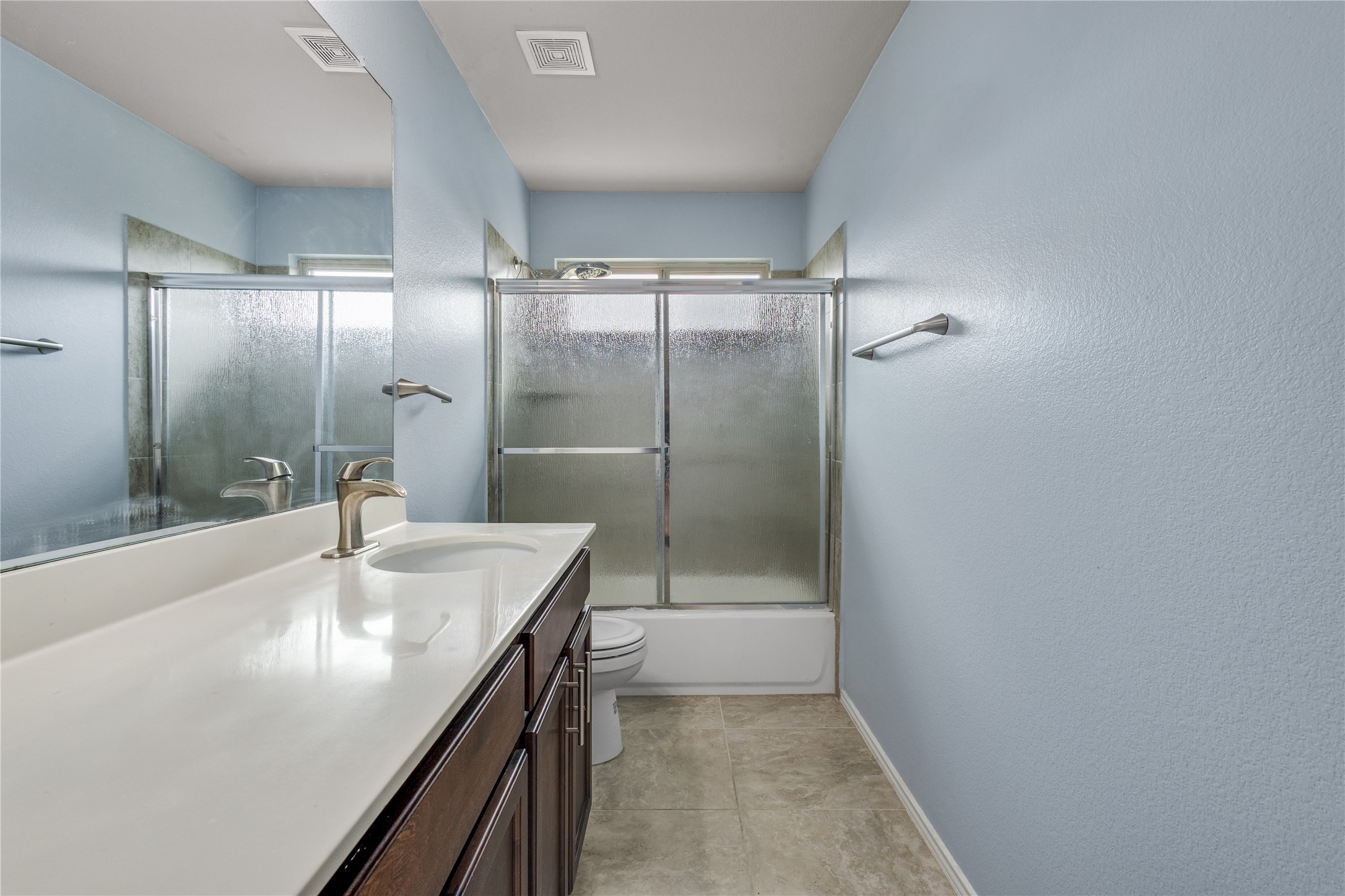 397 Limerick Road Buda, TX 78610 - Photo 25 of 33 The upstairs guest bathroom features a refreshing sky-blue accent wall that adds a cheerful splash of color.