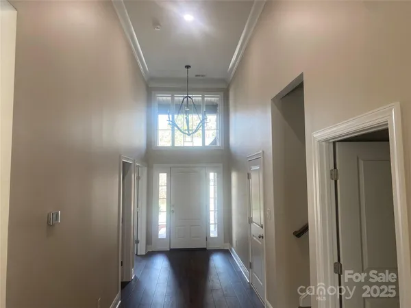 a view of a hallway with wooden floor and chandelier