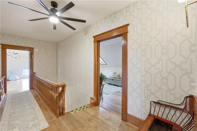 a view of a hallway with wooden floor and a ceiling fan