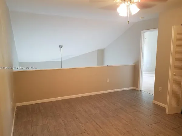 an empty room with wooden floor and fan