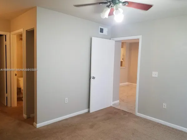 an empty room with closet and a chandelier fan