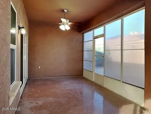 an empty room with chandelier fan and windows