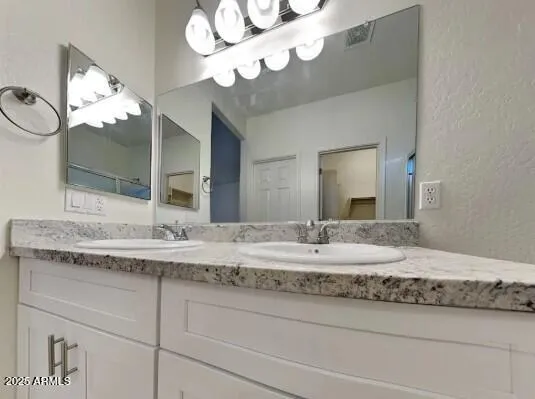 a bathroom with a granite countertop double vanity sink and a mirror