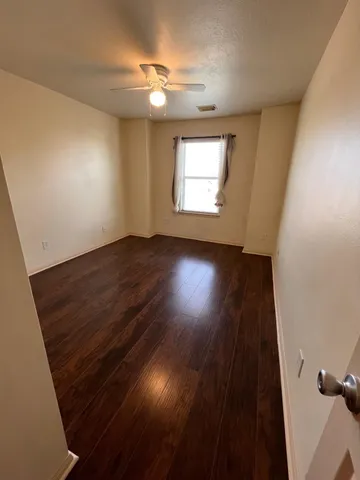 an empty room with wooden floor fan and windows