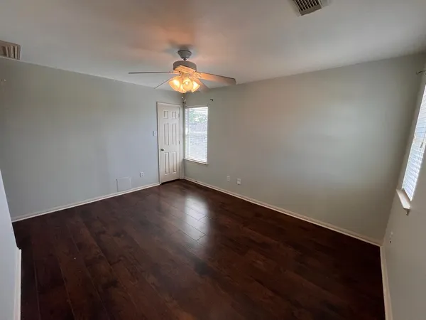 an empty room with wooden floor and windows