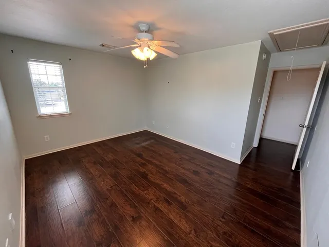 an empty room with wooden floor chandelier fan and windows