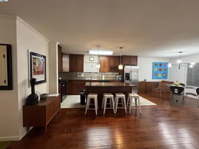 a living room with furniture a wooden floor and a kitchen view