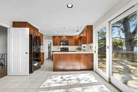 a room with stainless steel appliances kitchen island granite countertop a refrigerator and a sink