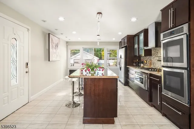 a kitchen with stainless steel appliances kitchen island granite countertop a refrigerator and a stove top oven