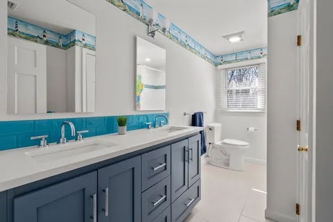 a bathroom with a granite countertop sink mirror and a toilet