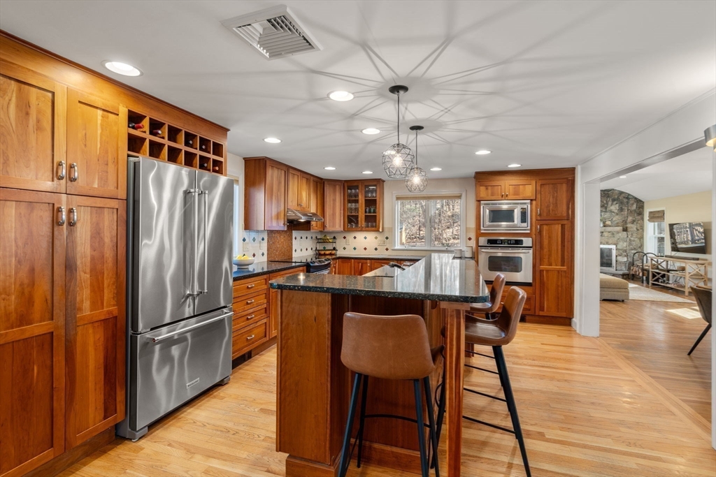 88 Robinwood Avenue Needham, MA 02492 - Photo 6 of 29 a kitchen with stainless steel appliances granite countertop a refrigerator a stove a sink a dining table and chairs with wooden floor