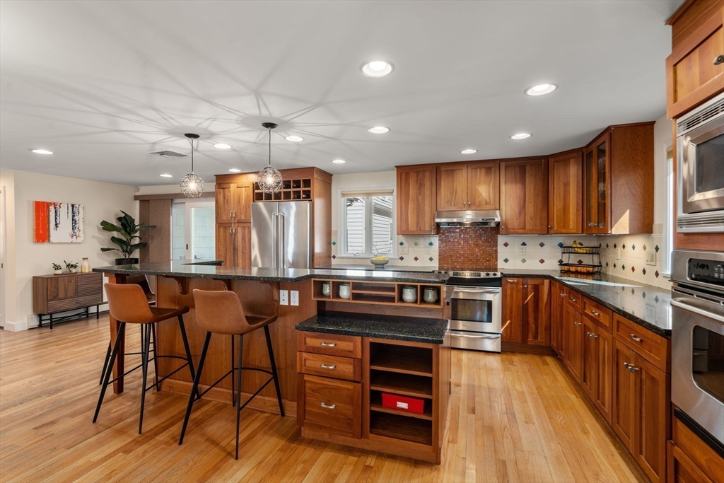 88 Robinwood Avenue Needham, MA 02492 - Photo 7 of 29 a kitchen with stainless steel appliances kitchen island granite countertop a table chairs and a refrigerator