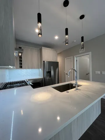 a large kitchen with stainless steel appliances a large counter top a refrigerator and a sink