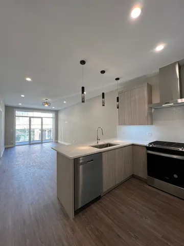 a large kitchen with stainless steel appliances granite countertop a large counter top and a stove with wooden floors