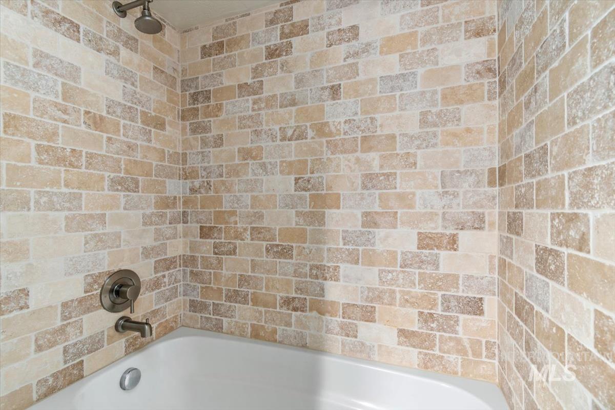 709 East Braemere Road Boise, ID 83702 - Photo 30 of 50 Tub/shower combination featuring subway-style brick-patterned tile, a showerhead, a tub spout, and a control handle